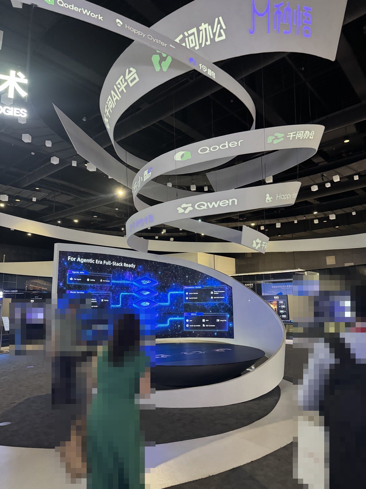Alibaba Cloud本社の展示。螺旋状の吊り看板。Qwen、Qoder、千問オフィス、Happy Oysterなどの名前が並ぶ